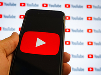 A man holding a smartphone with a Youtube logo and small YouTube logos displayed on a screen are seen in L’Aquila, Italy, on October 9th, 20...