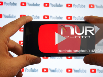 A man holding a smartphone with a Youtube logo and small YouTube logos displayed on a screen are seen in L’Aquila, Italy, on October 9th, 20...