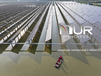 A worker checks photovoltaic equipment at a fishery-solar hybrid base in Suqian, China, on October 10, 2024. (