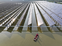 A worker checks photovoltaic equipment at a fishery-solar hybrid base in Suqian, China, on October 10, 2024. (