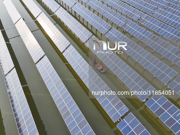 A worker checks photovoltaic equipment at a fishery-solar hybrid base in Suqian, China, on October 10, 2024. 