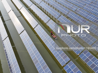 A worker checks photovoltaic equipment at a fishery-solar hybrid base in Suqian, China, on October 10, 2024. (