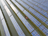 A worker checks photovoltaic equipment at a fishery-solar hybrid base in Suqian, China, on October 10, 2024. (