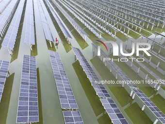 A worker checks photovoltaic equipment at a fishery-solar hybrid base in Suqian, China, on October 10, 2024. (