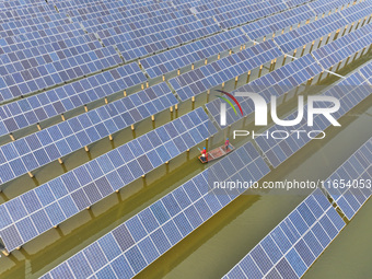 A worker checks photovoltaic equipment at a fishery-solar hybrid base in Suqian, China, on October 10, 2024. (