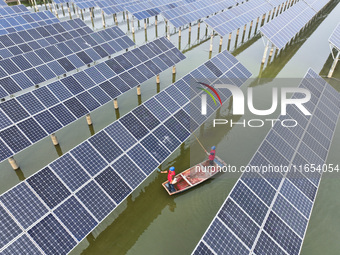 A worker checks photovoltaic equipment at a fishery-solar hybrid base in Suqian, China, on October 10, 2024. (