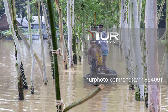 A father takes his children across floodwaters in a boat in a village of Jhenaigati upazila in Sherpur district, Bangladesh, on October 6, 2...