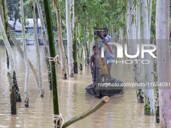 A father takes his children across floodwaters in a boat in a village of Jhenaigati upazila in Sherpur district, Bangladesh, on October 6, 2...