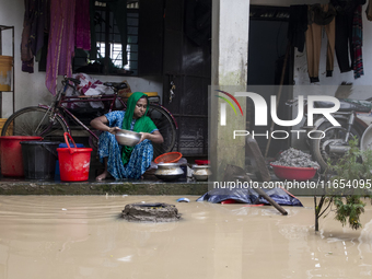 A woman washes essential items in floodwaters in front of her house in a village in Jhenaigati upazila of Sherpur district, Bangladesh, on O...