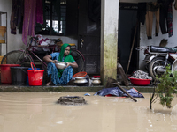 A woman washes essential items in floodwaters in front of her house in a village in Jhenaigati upazila of Sherpur district, Bangladesh, on O...