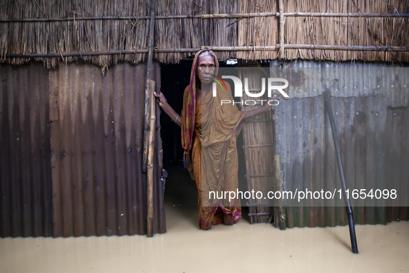 An elderly woman stands in front of her house in knee-deep flood water in a village in Jhenaigati upazila of Sherpur district in Sherpur, Ba...