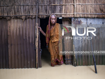 An elderly woman stands in front of her house in knee-deep flood water in a village in Jhenaigati upazila of Sherpur district in Sherpur, Ba...