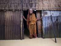 An elderly woman stands in front of her house in knee-deep flood water in a village in Jhenaigati upazila of Sherpur district in Sherpur, Ba...