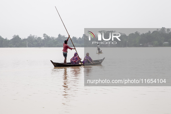 In Sherpur, Bangladesh, on October 6, 2024, a few men and women cross the floodwaters using boats and banana rafts in a village of Jhenaigat...