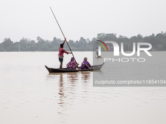 In Sherpur, Bangladesh, on October 6, 2024, a few men and women cross the floodwaters using boats and banana rafts in a village of Jhenaigat...