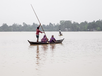 In Sherpur, Bangladesh, on October 6, 2024, a few men and women cross the floodwaters using boats and banana rafts in a village of Jhenaigat...