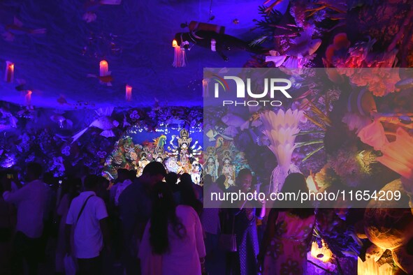 Devotees throng at a community 'puja pandal' themed on 'under the sea' during the Durga Puja festival in the Nagaon district of Assam, India...