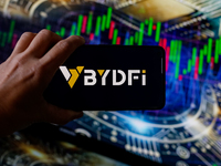 In this photo illustration, the BYDFI logo is seen displayed on a smartphone screen against a computer screen displaying a stock market grap...