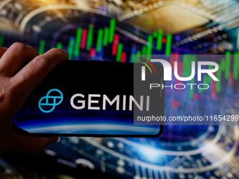 In this photo illustration, the Gemini logo is seen displayed on a smartphone screen against a computer screen displaying a stock market gra...