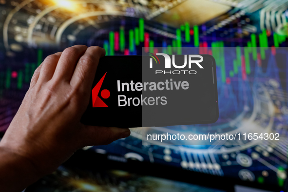 In this photo illustration, the Interactive Brokers logo is seen displayed on a smartphone screen against a computer screen displaying a sto...