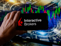 In this photo illustration, the Interactive Brokers logo is seen displayed on a smartphone screen against a computer screen displaying a sto...