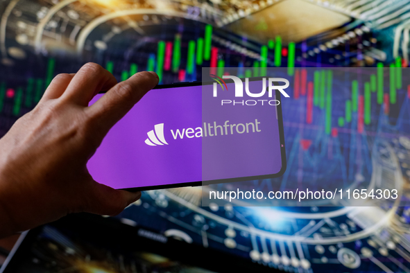 In this photo illustration, the Wealthfront logo is seen displayed on a smartphone screen against a computer screen displaying a stock marke...