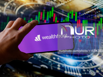 In this photo illustration, the Wealthfront logo is seen displayed on a smartphone screen against a computer screen displaying a stock marke...