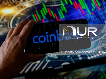 In this photo illustration, the Coinbase logo is seen displayed on a smartphone screen against a computer screen displaying a stock market g...