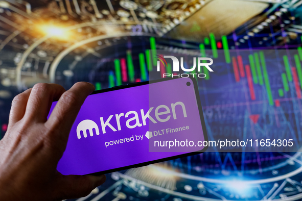 In this photo illustration, the Kraken logo is seen displayed on a smartphone screen against a computer screen displaying a stock market gra...