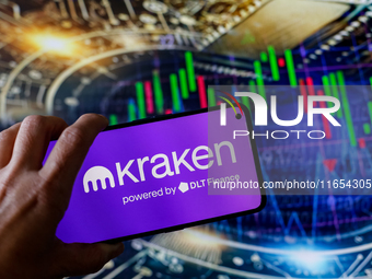 In this photo illustration, the Kraken logo is seen displayed on a smartphone screen against a computer screen displaying a stock market gra...