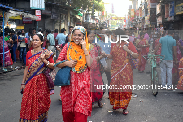 A woman talks on her mobile while walking inside a market in Kolkata, India, on October 10, 2024. 