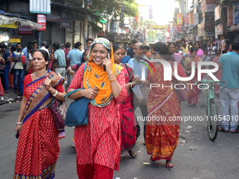 A woman talks on her mobile while walking inside a market in Kolkata, India, on October 10, 2024. (