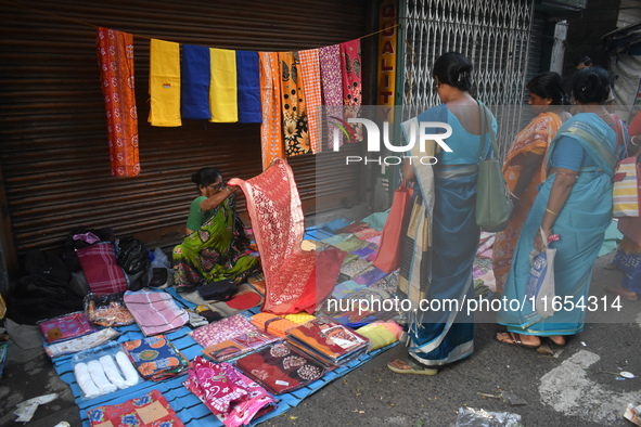 A woman displays a saree to her customer inside a market in Kolkata, India, on October 10, 2024. 