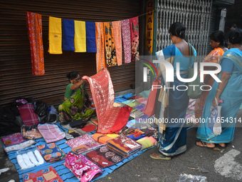 A woman displays a saree to her customer inside a market in Kolkata, India, on October 10, 2024. (