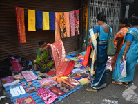 A woman displays a saree to her customer inside a market in Kolkata, India, on October 10, 2024. (