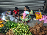 A woman holds her baby in her arms while selling vegetables inside a market in Kolkata, India, on October 10, 2024. (