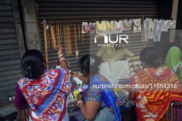 Women buy imitation jewelry on the occasion of the Durga Puja festival from a roadside shop inside a market in Kolkata, India, on October 10...