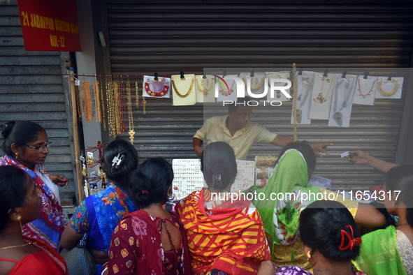 Women buy imitation jewelry on the occasion of the Durga Puja festival from a roadside shop inside a market in Kolkata, India, on October 10...