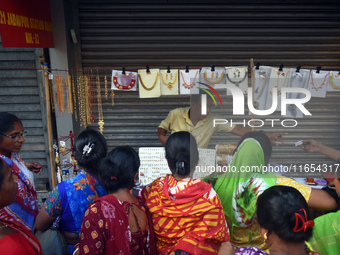 Women buy imitation jewelry on the occasion of the Durga Puja festival from a roadside shop inside a market in Kolkata, India, on October 10...