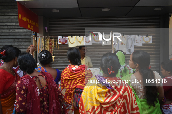 Women buy imitation jewelry on the occasion of the Durga Puja festival from a roadside shop inside a market in Kolkata, India, on October 10...