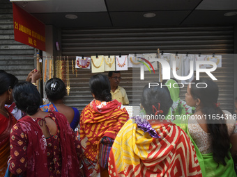 Women buy imitation jewelry on the occasion of the Durga Puja festival from a roadside shop inside a market in Kolkata, India, on October 10...