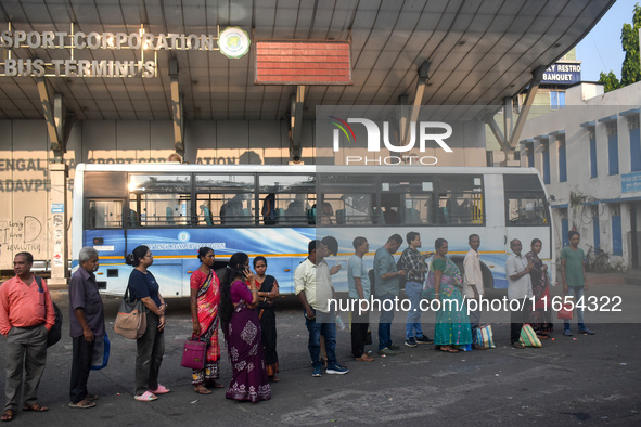 People stand in a queue inside a bus stand to pick up a bus in Kolkata, India, on October 10, 2024. 