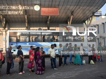 People stand in a queue inside a bus stand to pick up a bus in Kolkata, India, on October 10, 2024. (