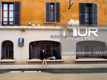 Two young people sit next to a flooded street in Coulommiers, Seine-et-Marne department, east of Paris, on October 10, 2024, as the heavy ra...