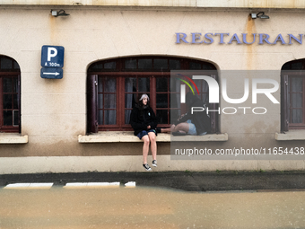 Two young people sit next to a flooded street in Coulommiers, Seine-et-Marne department, east of Paris, on October 10, 2024, as the heavy ra...