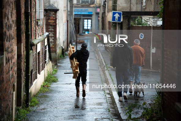 Three men bring tools to clean a flooded house in Coulommiers, Seine-et-Marne department, east of Paris, on October 10, 2024, as the heavy r...