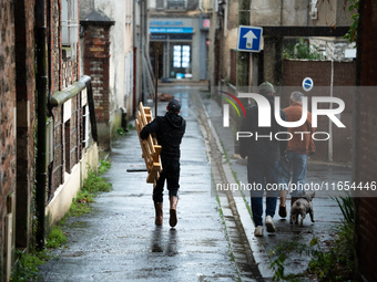 Three men bring tools to clean a flooded house in Coulommiers, Seine-et-Marne department, east of Paris, on October 10, 2024, as the heavy r...