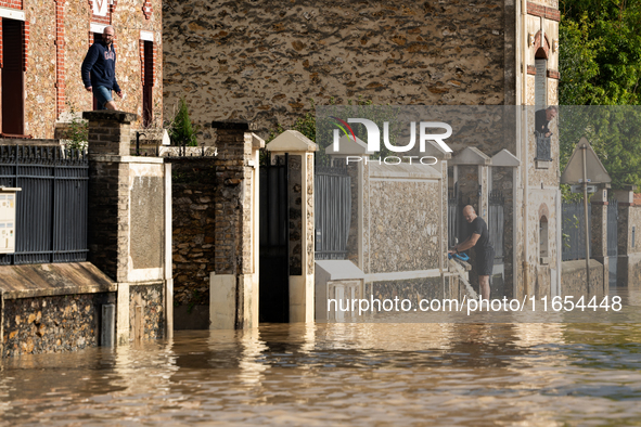 A man pulls water off his house on a flooded street in Coulommiers, Seine-et-Marne department, east of Paris, on October 10, 2024, as the he...