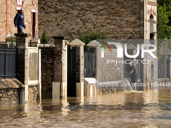 A man pulls water off his house on a flooded street in Coulommiers, Seine-et-Marne department, east of Paris, on October 10, 2024, as the he...