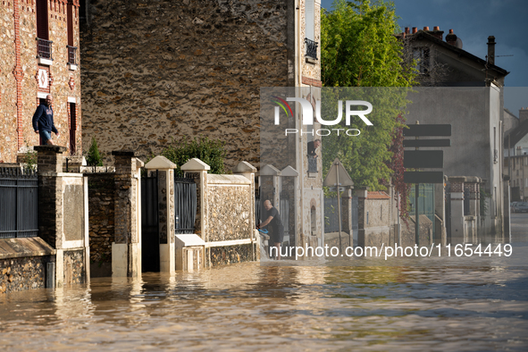 A man pulls water off his house on a flooded street in Coulommiers, Seine-et-Marne department, east of Paris, on October 10, 2024, as the he...